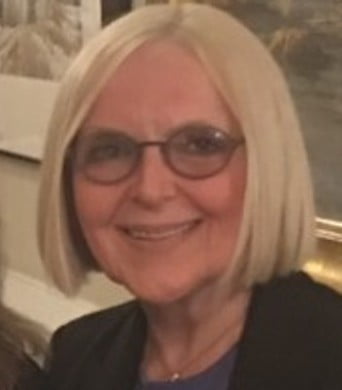 a woman with blonde hair and glasses smiling.