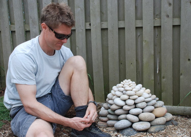 a man sitting on the ground next to a pile of rocks.