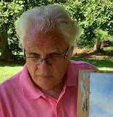 a man in a pink shirt holding a painting.