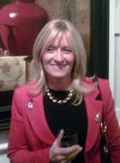 a woman in a red jacket holding a glass of wine.