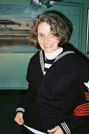 a woman in a sailor's uniform smiling for the camera.