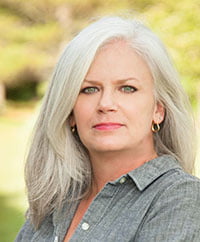 a woman with grey hair and blue eyes.