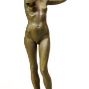 Bronze statue of a nude woman with high heels holding a deer's antlers to the sides of her head.