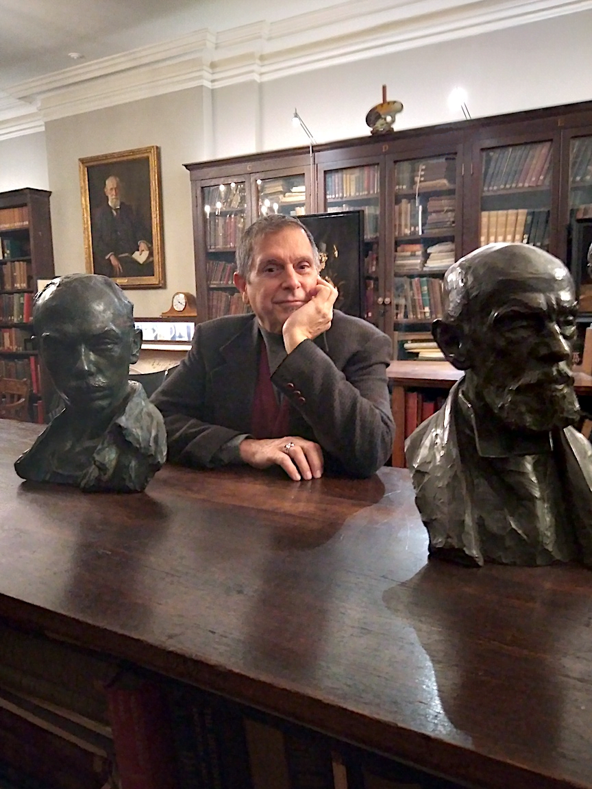Anthony Bellov sits at a table in the Smith library between two busts.