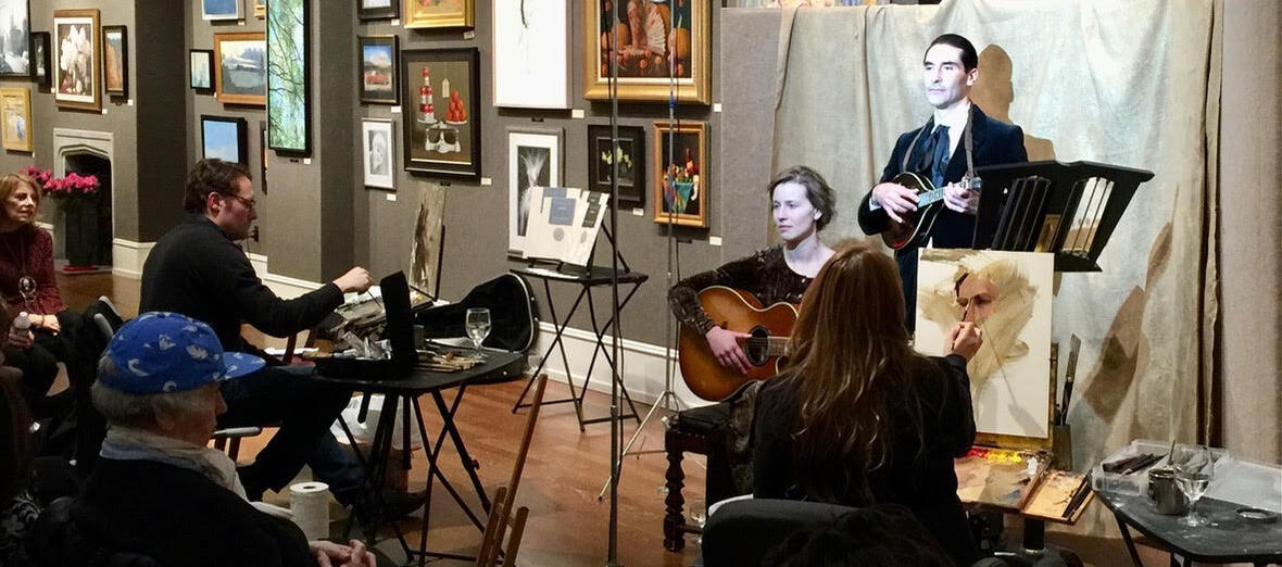 An audience watches a guitar and mandolin duo pose in a bright light as artists paints them.