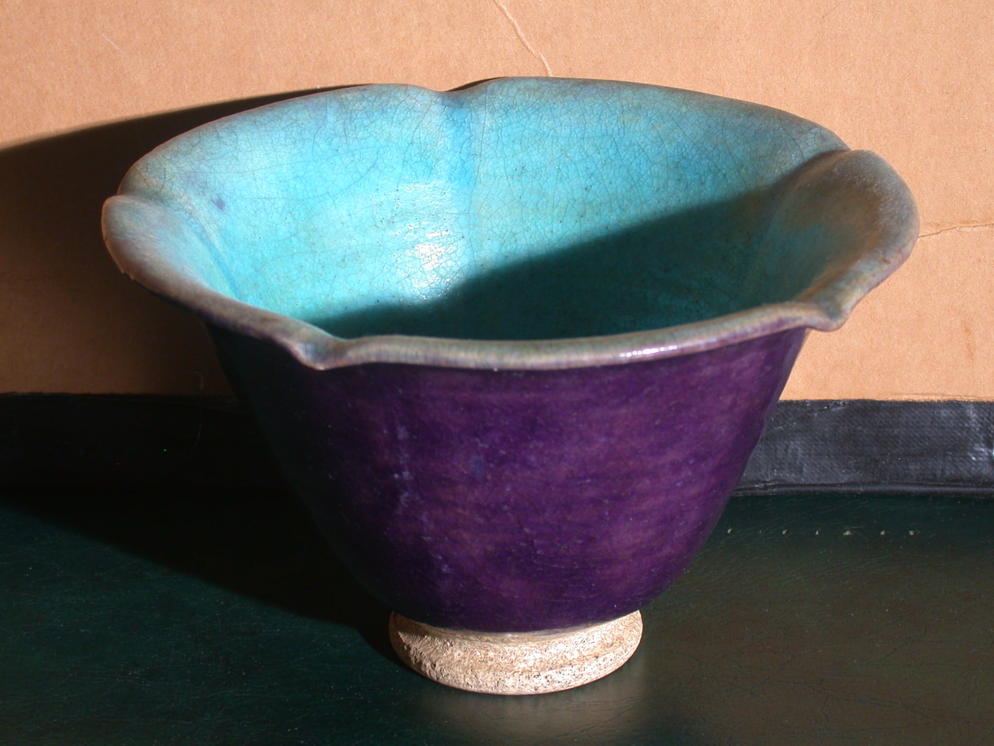 A bowl that flares out a little at the top with plum glaze exterior and a turquoise glaze interior with faince finish.