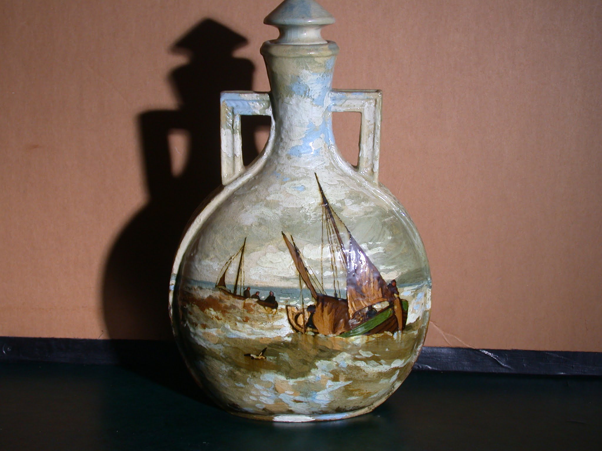 A ceramic jug, with an ocean scene depicting a pair of small boats in the waves.