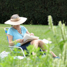 a woman sitting in a lawn chair, going through papers.
