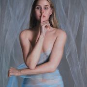 A young woman holding her finger to her mouth, wearing only a light blue sheer material wrapped around her middle.