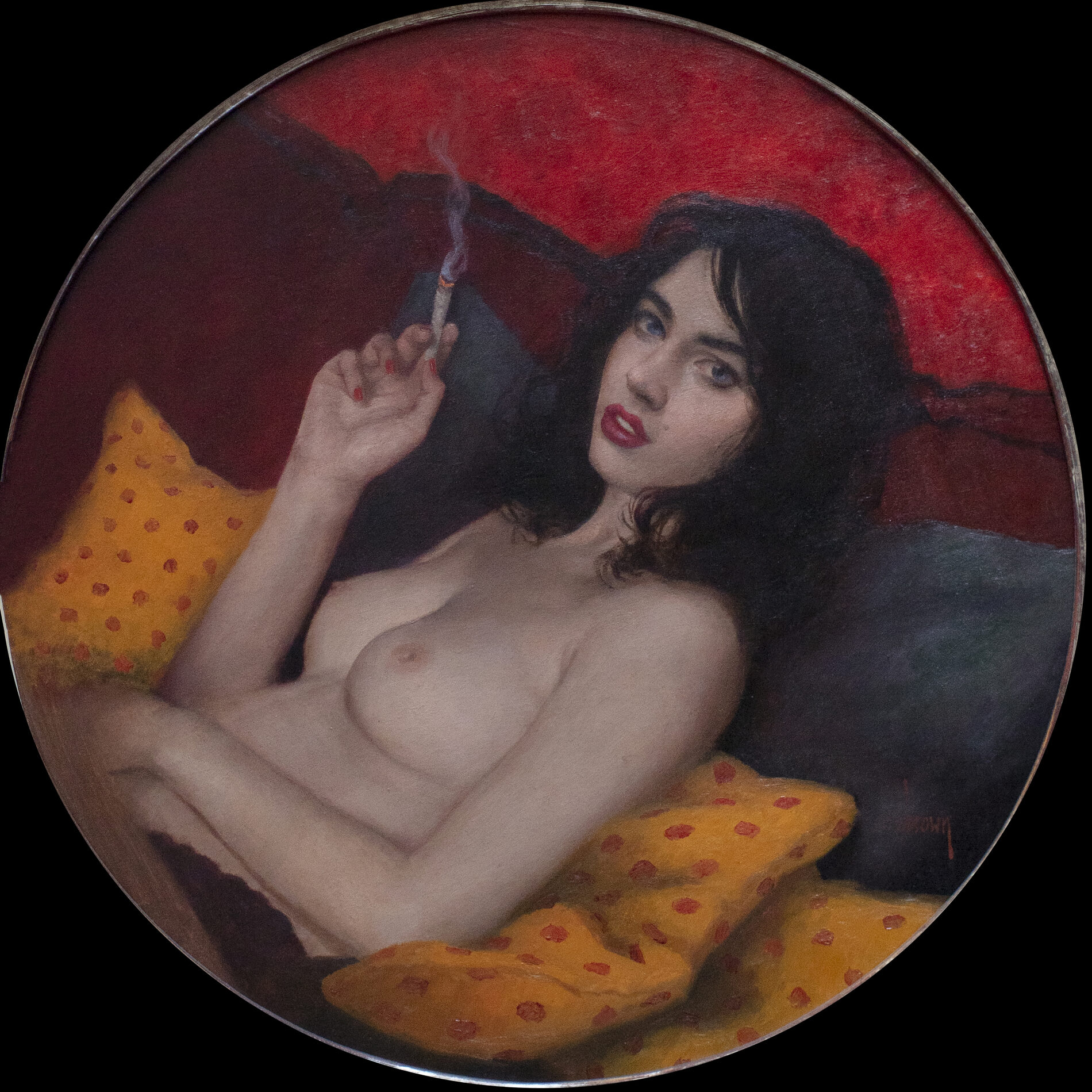 In a circular frame, a shirtless woman issmoking a cigarette while reclining on pilows.