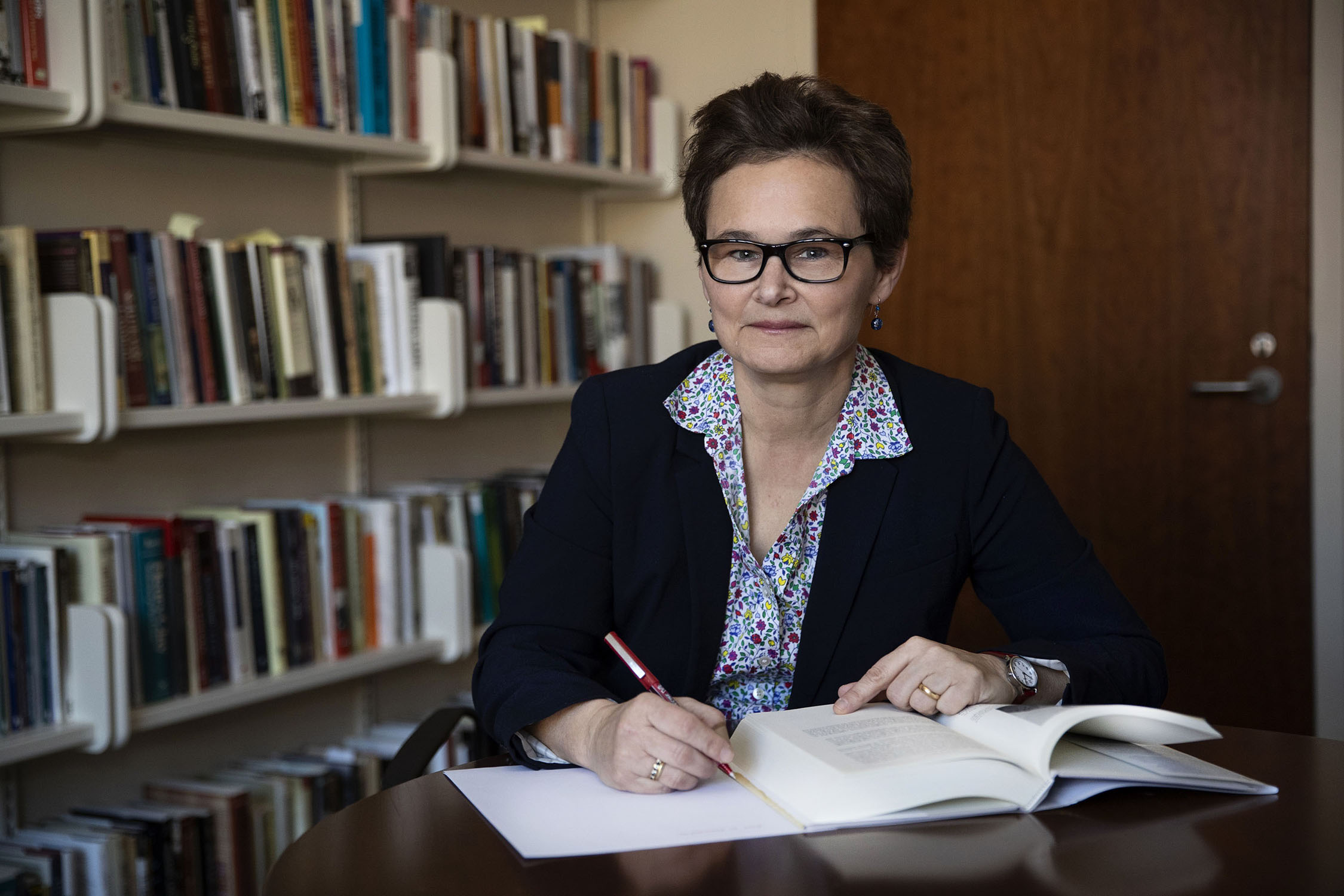 Elizabeth R. Varon is a short-haired woman with glasses, sitting at a table at a library, writing notes next to an open book.