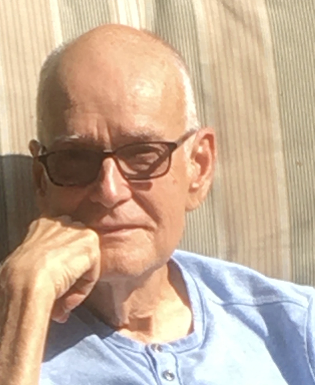 An older man with glasses sitting in a chair.