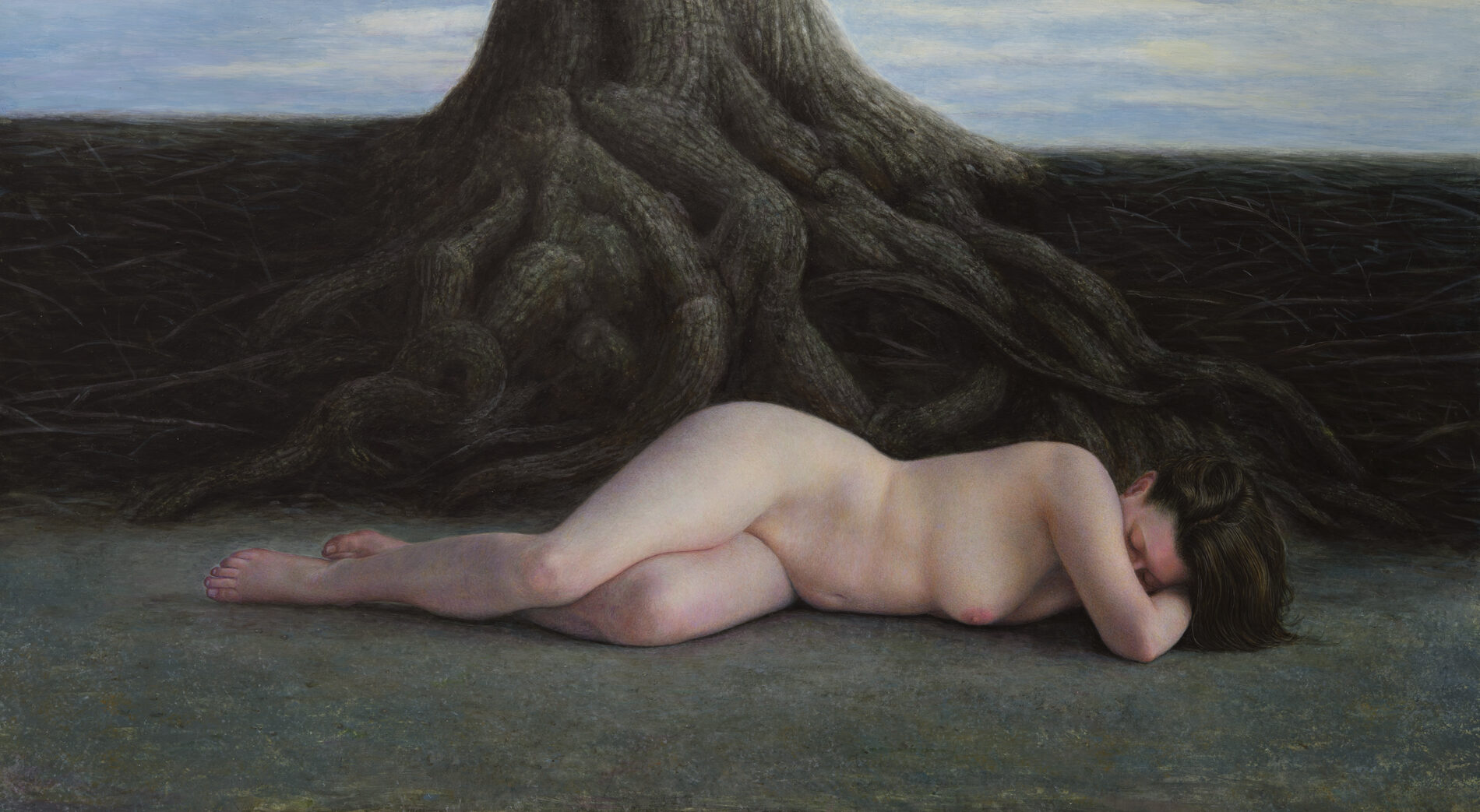 A nude woman laying at the base of a large tree with exposed roots.