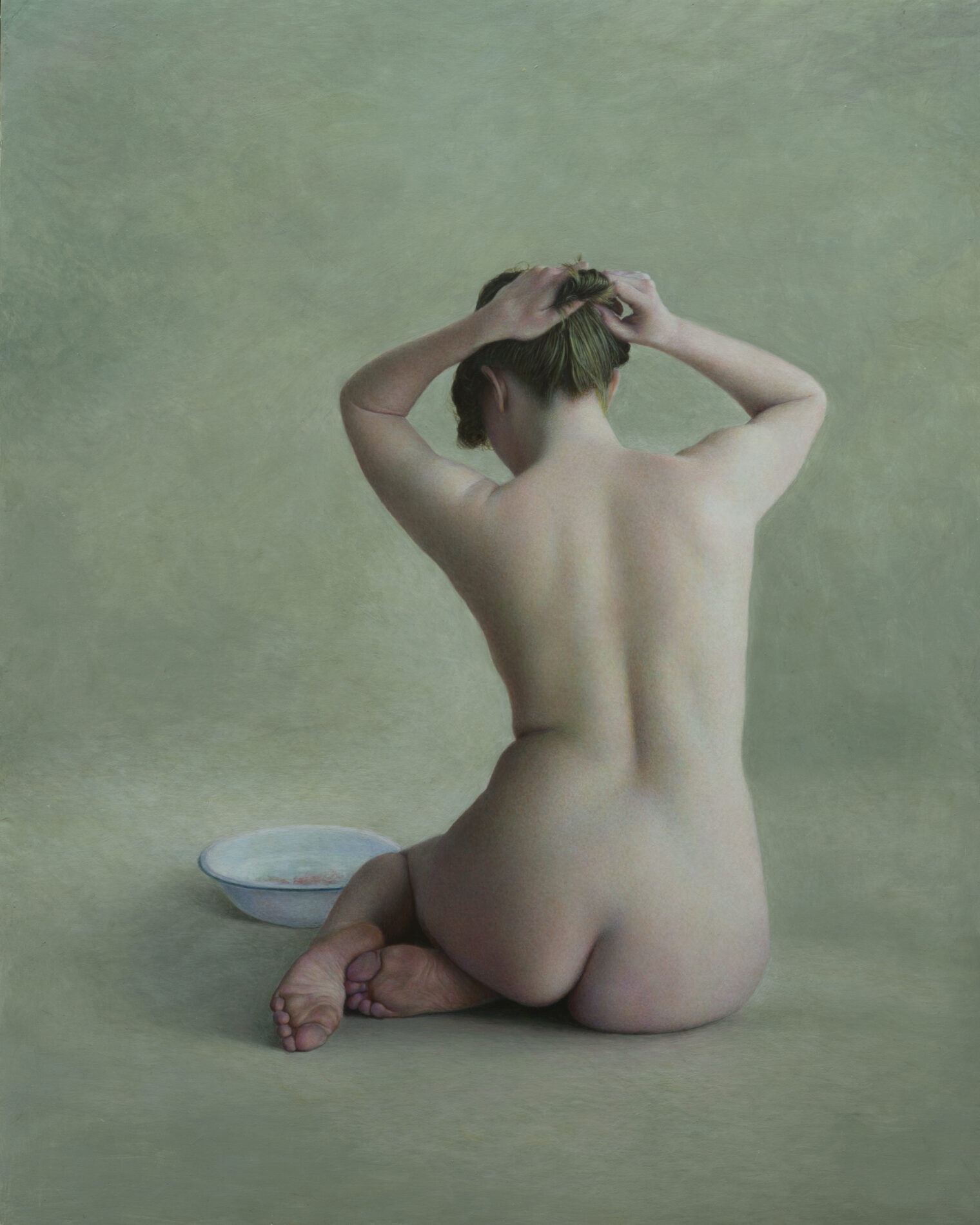 A nude woman, from behind, sits on the ground, fixing her hair bun, a ceramic bowl in front of her.