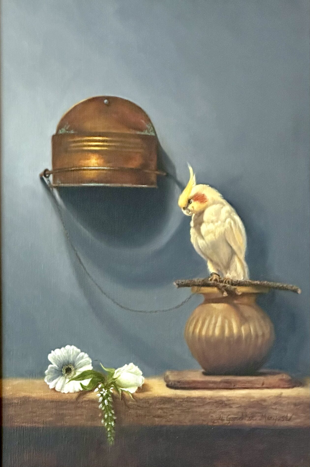 A yellow cockatiel perched on sticks on a vase with white flowers next to it on the wooden shelf.