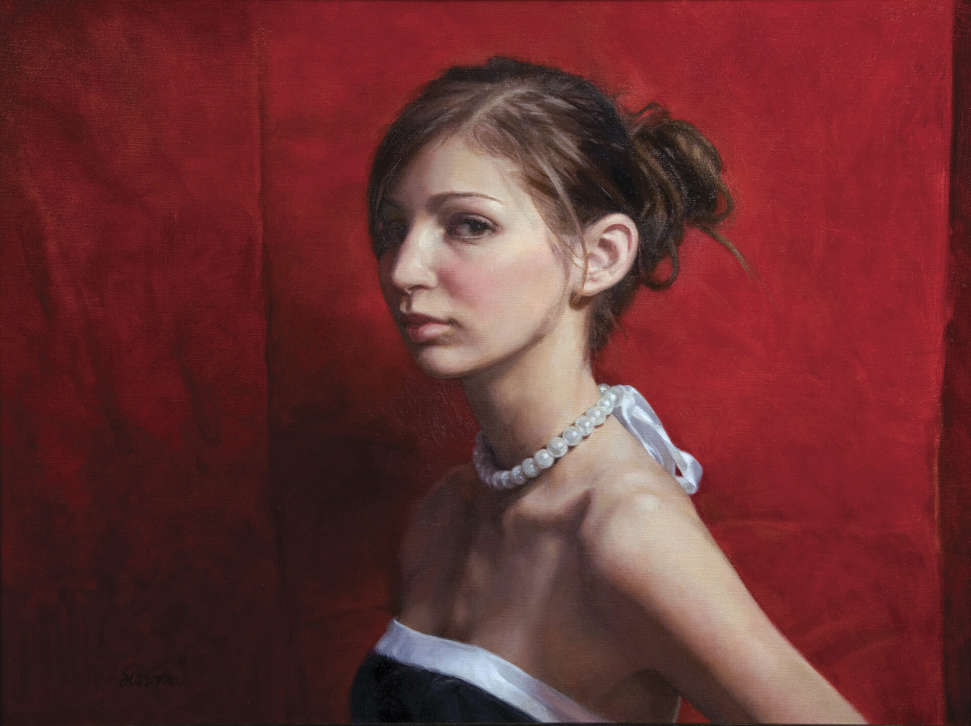 From the chest up, a young woman in a white and black dress with pearls in front of a red backdrop.