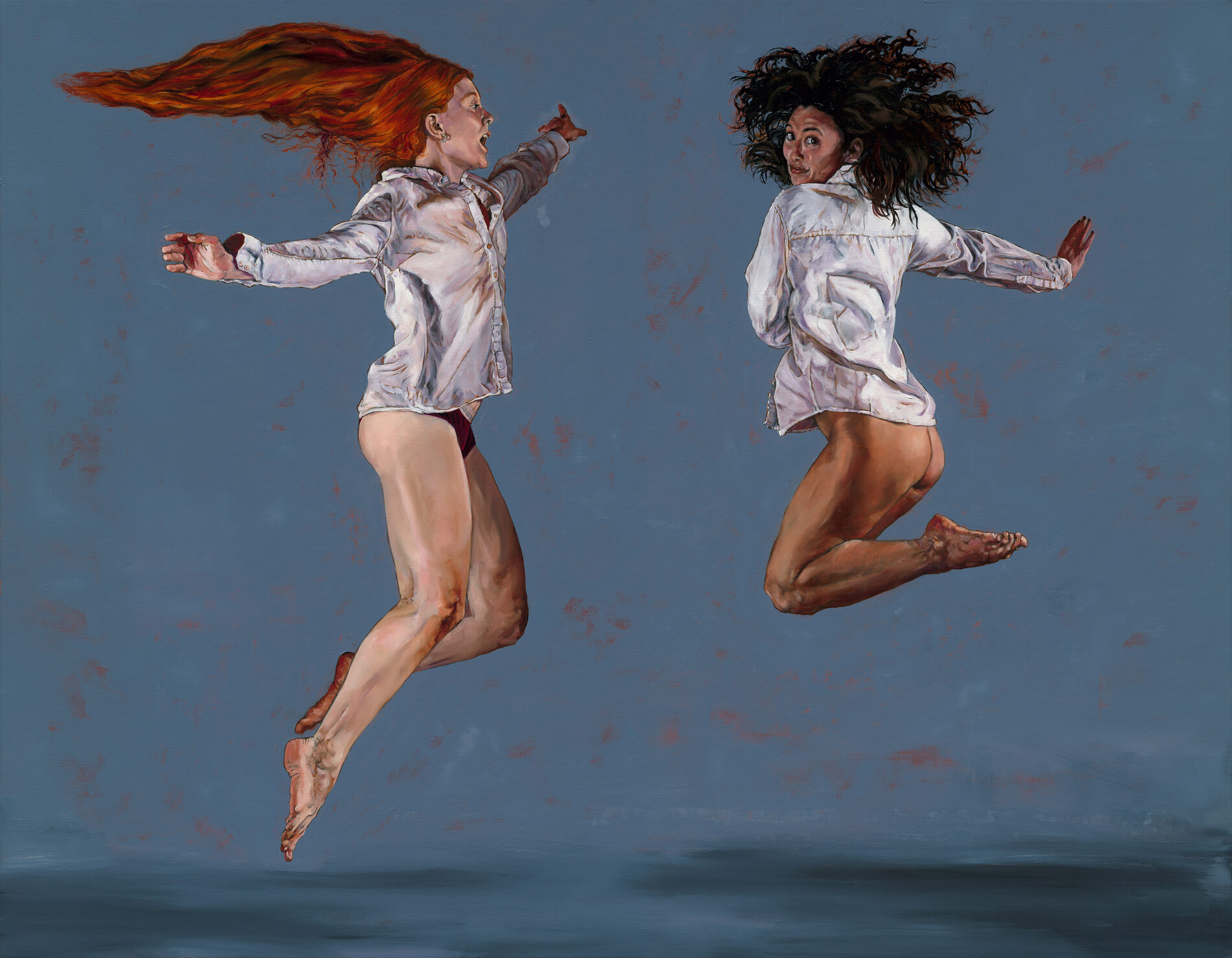 Two young women in underwear and button down shirts jumping in the air.