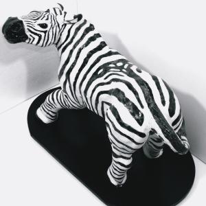 A black and white zebra figurine on a black base.