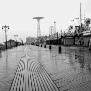 A black and white photo of a boardwalk in the rain.