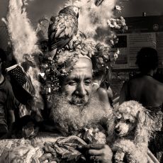 A man in a feathered costume holding a dog.
