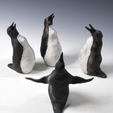 Four black and white penguin figurines on a white surface.