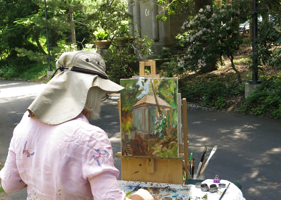 Artist painting outdoors with a canvas and palette, capturing a natural scene in daylight.
